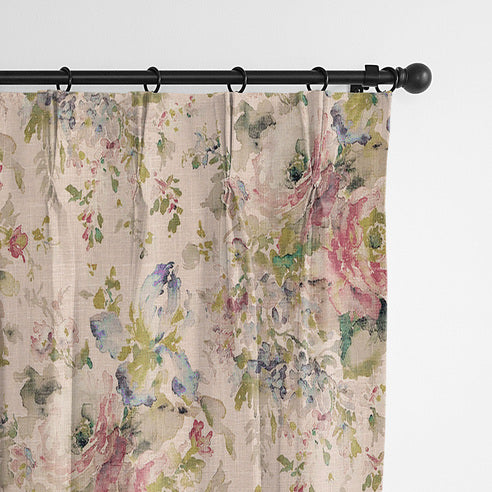 Close-up of Blossom Blush floral drapery panels hanging from rings on a black curtain rod.