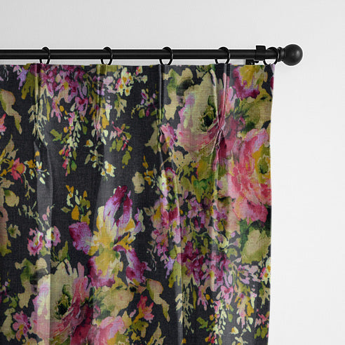 Close-up of Blossom Charcoal drapery panels hanging from black rings, with pink and green florals on a charcoal background.