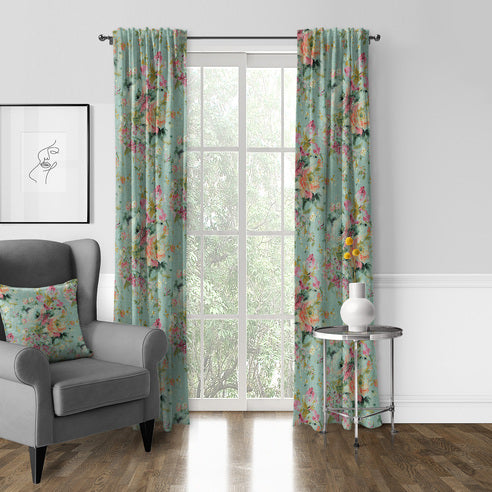 Blossom Eggshell pole top floral drapery panels framing a window beside a grey armchair and silver side table.