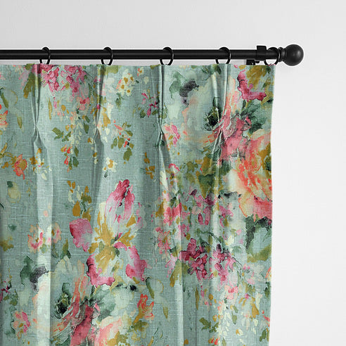 Close-up of Blossom Eggshell drapery panels hanging from black rings, with pink florals on a pale blue-green background.