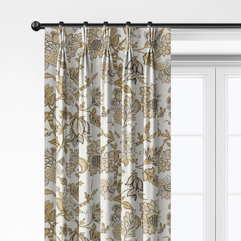 Close-up of Bronte Gold pleated drapery hanging from rings, showing gold and taupe flowers on a light background.