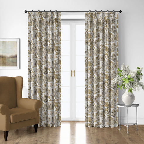 Bronte Gold floral drapery panels framing white French doors beside a gold-toned armchair and silver side table.