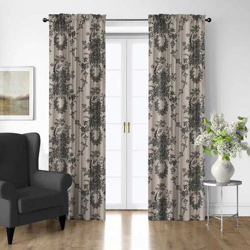 Country Lane Ebony pole top patterned drapery panels framing white French doors, with a charcoal armchair and flower-filled vase nearby.