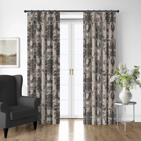 Country Lane Ebony drapery panels with dark floral motifs framing white French doors beside a charcoal armchair.