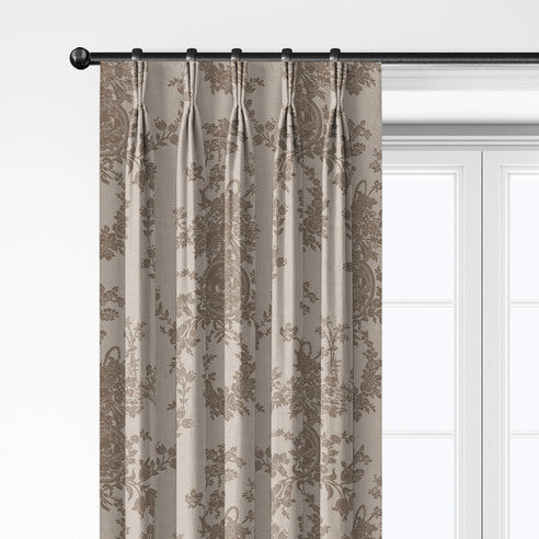 Close-up of Country Lane Natural pleated drapery hanging from rings, showing taupe floral and medallion motifs on beige.