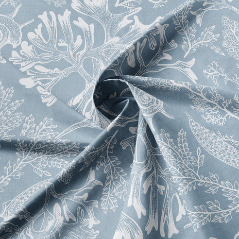Close-up of Shellabrate Cornflower Blue fabric showing white seashell and coral motifs on a blue background
