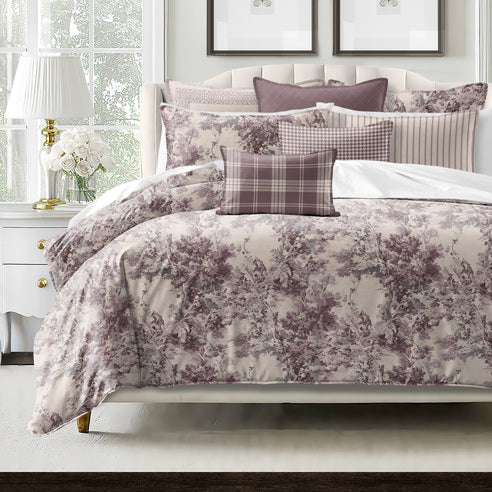 Bed with floral patterned comforter and pillows in a bedroom setting.