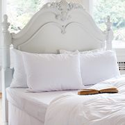 St. Genève Waterproof Mattress Protector on a white bed with ornate headboard and pillows