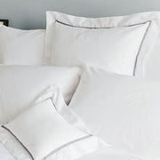 Close-up of St. Genève Capri Clair white sateen pillowcases showing elegant grey satin stitch border detail