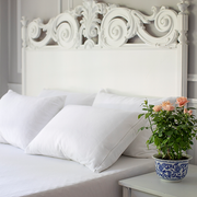 Elegant white bedroom with ornate headboard featuring St. Genève mattress encasement and pillow protectors