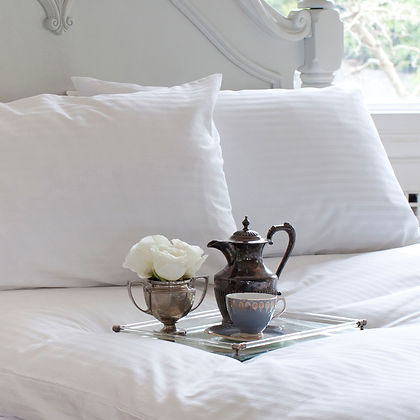  Luxury white bed with pillows and silver tea tray, styled with St. Genève Luxury Topper Protector