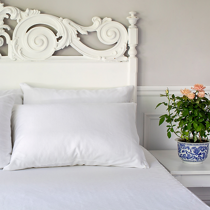 Luxury white bedroom with carved headboard and pink roses showcasing St. Genève pillow encasement