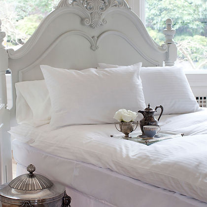 Elegant white bedroom with ornate headboard and St. Genève Luxury Topper Protector on bed