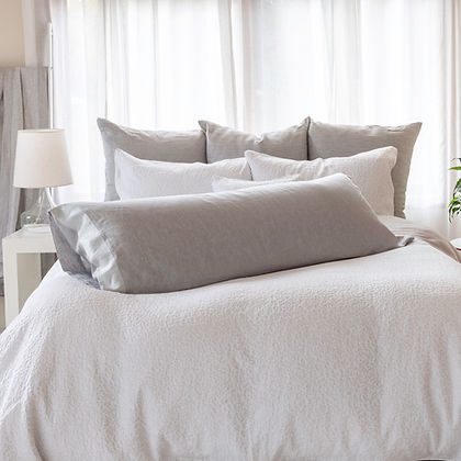 St. Genève body pillow in a grey pillowcase styled on a made bed with white duvet and decorative pillows

