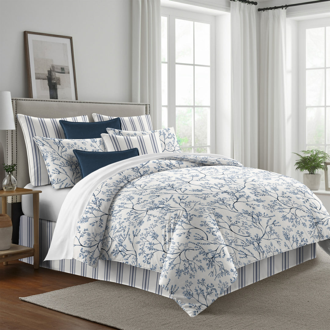 Tinsley comforter set with blue leafy branches on antique white, styled with matching shams and navy accent pillows