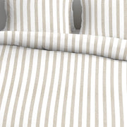 closer view: Close-up of Ally sand and white striped cotton duvet cover folded back beneath matching pillows