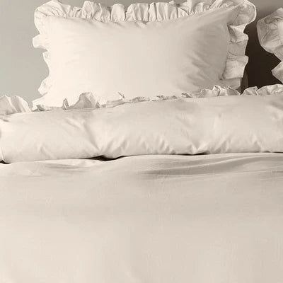 closer view: Close-up of Armance natural duvet cover folded back beneath a matching ruffled pillow