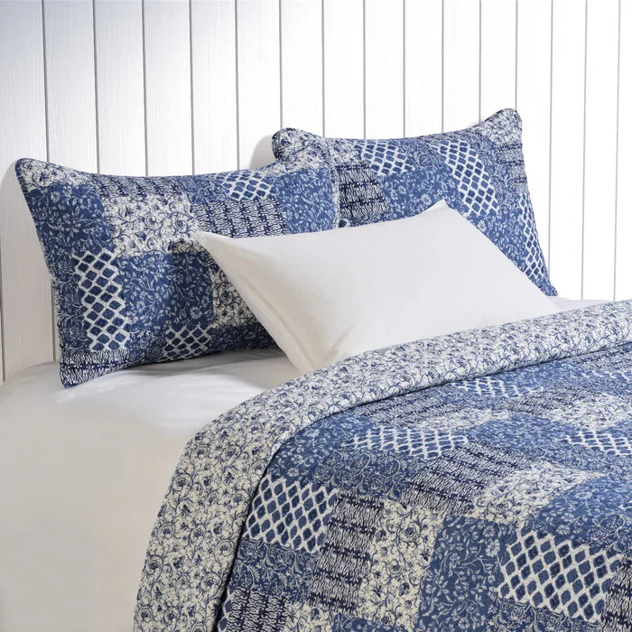 Donalda blue and ivory patchwork style quilt set on a bed