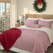 Holly red and white striped quilt on a bed with matching pillow shams, a red throw and a holiday wreath above the wooden headboard.