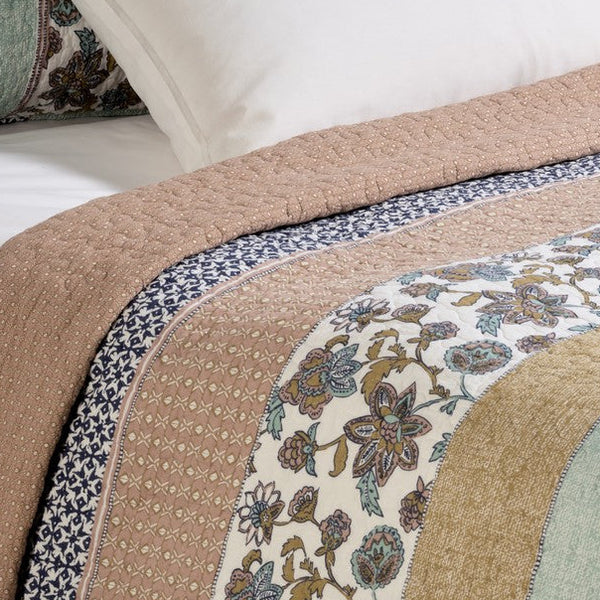 Kombucha printed quilt set in aqua, navy and dusty rose on a bed

