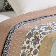 Kombucha printed quilt set in aqua, navy and dusty rose on a bed
