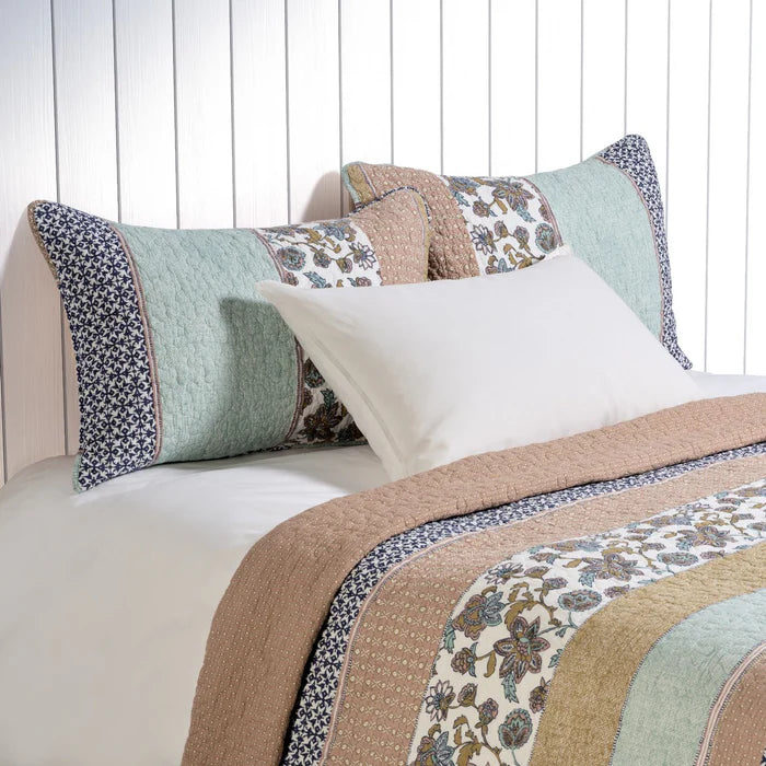 Kombucha printed quilt set in aqua, navy and dusty rose on a bed
