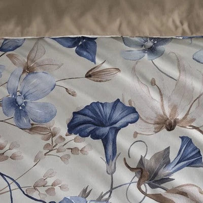 closer view: Close-up of Loïse floral duvet cover showing blue and taupe flowers beneath a folded taupe reverse