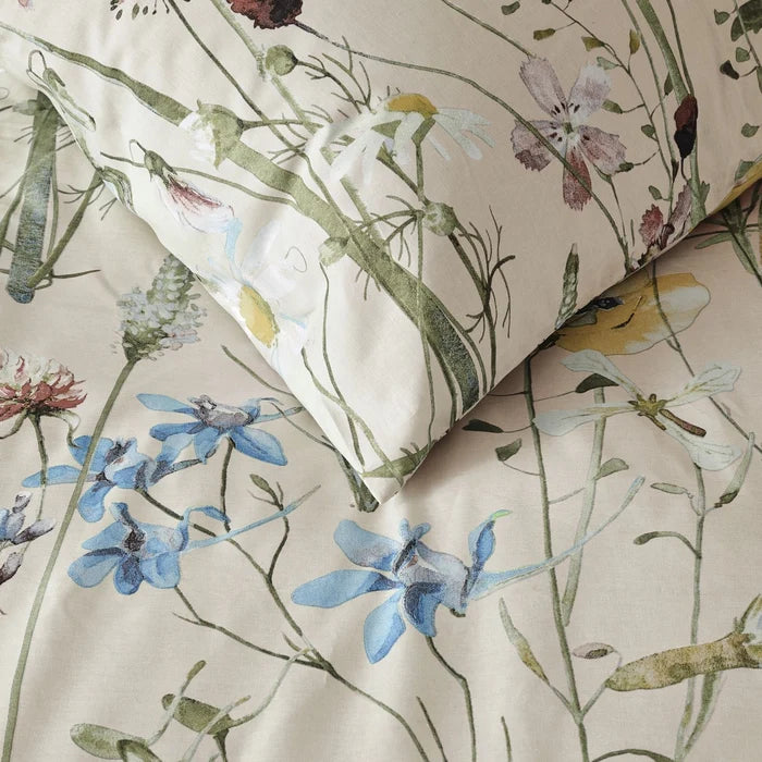 fabric detail: Melodie cotton duvet cover and matching pillowcase showing pastel wildflowers and leafy stems on a cream background

