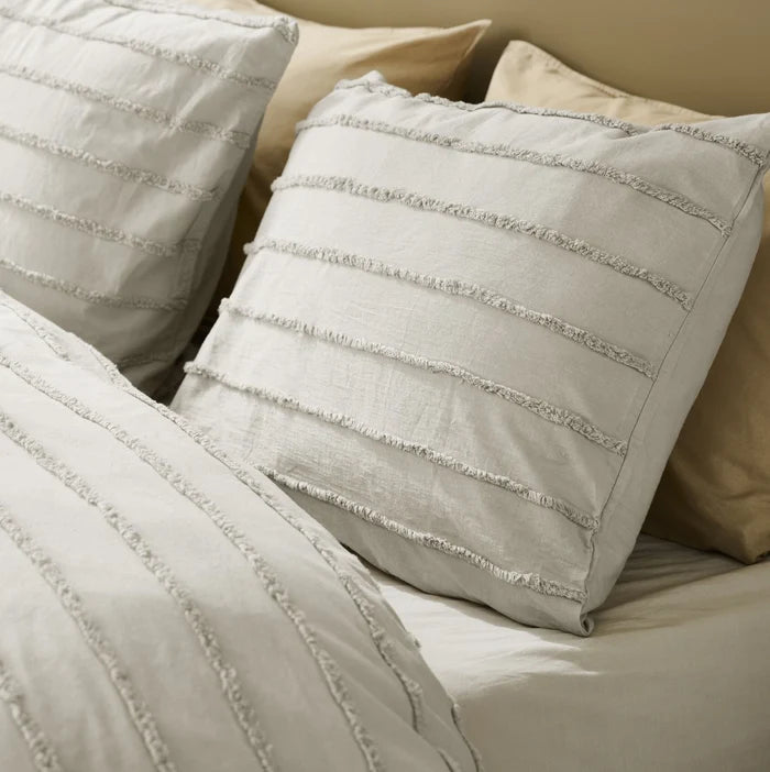 pillow detail: Matching light neutral pillowcases with tufted horizontal stripes beside the textured cotton duvet cover