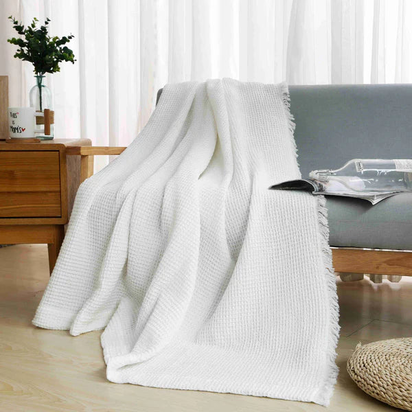 White textured blanket draped over a sofa in a living room setting.