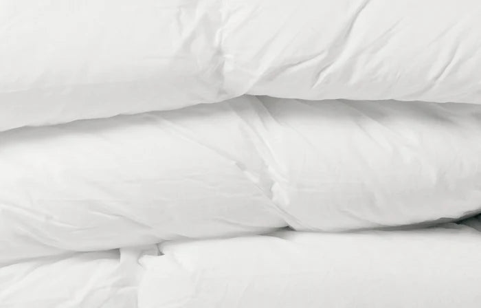 All seasons microfiber duvet styled on a bed with white pillows and soft lighting