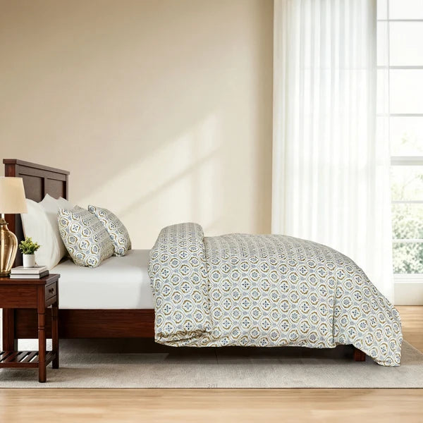 Side view of Motif patterned duvet cover and matching pillowcases on a wooden bed.
