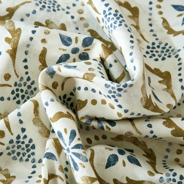 Close-up of Motif fabric showing blue floral shapes and olive green details on an ivory background.
