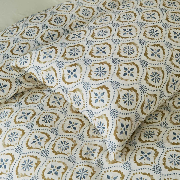 Close-up of Motif pillowcase and duvet cover featuring a repeating blue and olive green block print on ivory.
