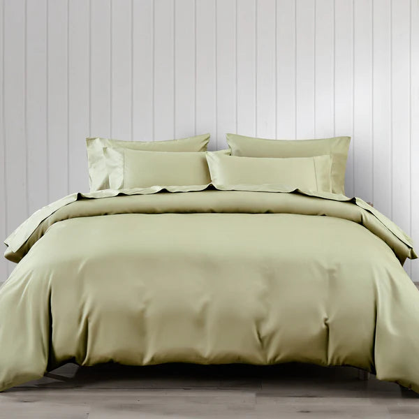 Green bed skirt set on a bed against a light wooden paneled wall.