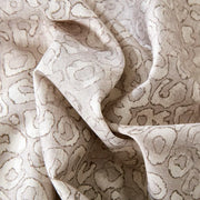 Close-up of softly folded Sable fabric showing an animal-inspired pattern in cream and taupe.
