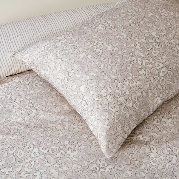 Sable animal-print pillowcase resting on the matching duvet cover beside a coordinating striped pillowcase.
