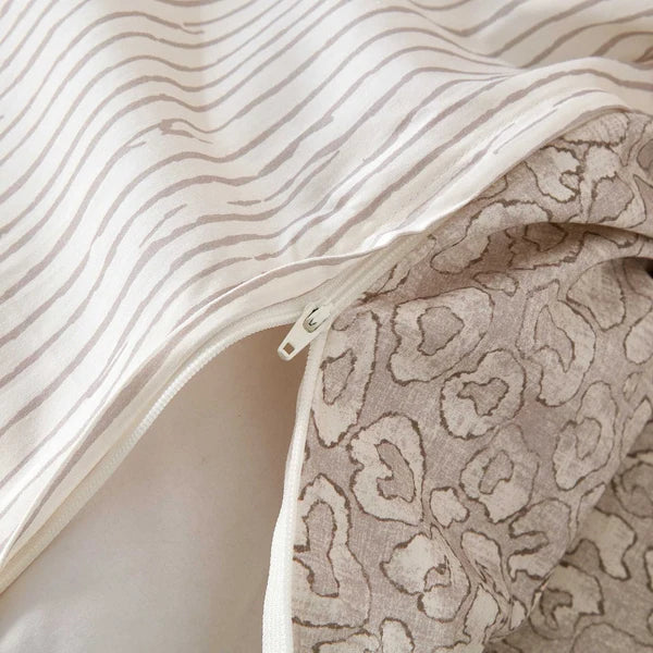 Close-up of the Sable duvet cover zipper showing the neutral animal-print front and striped reverse.
