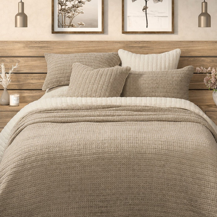 Spirit taupe waffle cotton quilt on a bed with matching taupe pillow shams, cream bedding and a wooden headboard.