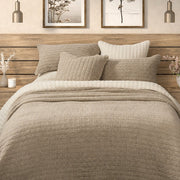 Spirit taupe waffle cotton quilt on a bed with matching taupe pillow shams, cream bedding and a wooden headboard.